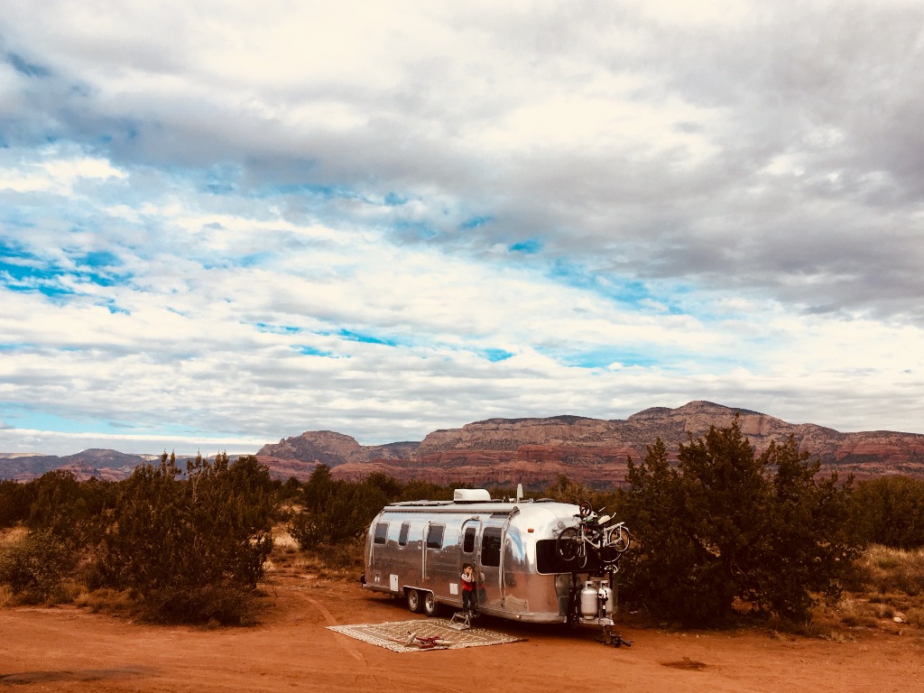Kids playing outside vintage Airstream at lakeside campground