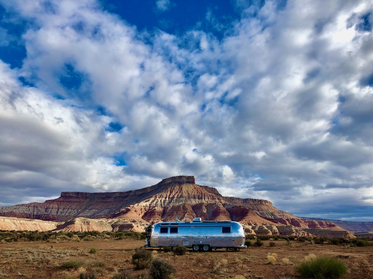 Airstream parked beneath dramatic desert butte